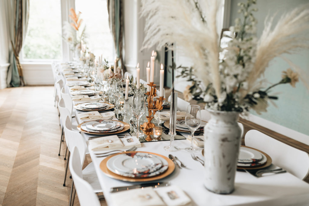 Lange dinertafel bruiloft met servies en bloemen in neutrale kleuren